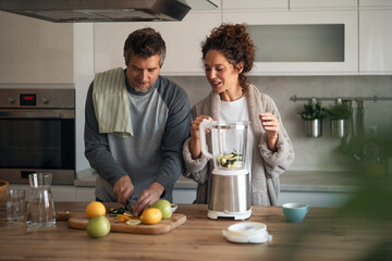 Couple Preparing Fruit Smoothies in Modern Kitchen With Blender and Cutting Board