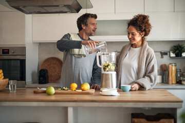 Couple In Modern Kitchen Making Smoothie Together With Blender And Fresh Fruit