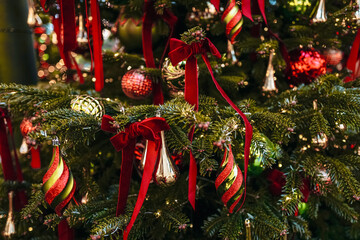 Natural spruce branches decorated with red velvet Christmas bows and gold decor, New Year magic details