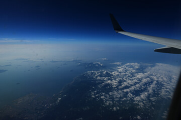 Fototapeta premium 旅行に向かう飛行機の中から撮った雲と青い空