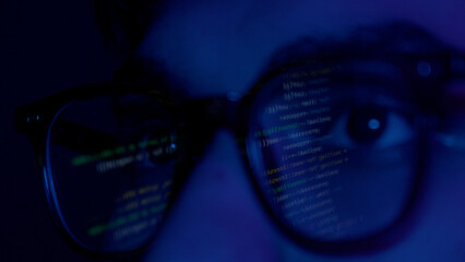 Close up of man's face with binary code reflection on glasses