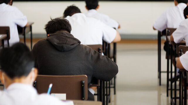 Students sit on chairs in the examination room or classroom, wearing their student uniforms, to take the exam with stress.