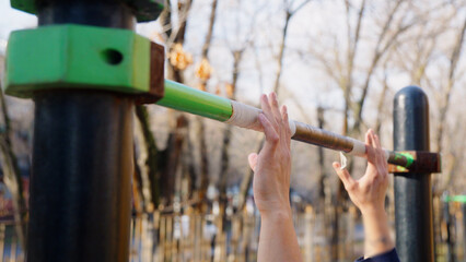 People hands holding high bar during group workout outdoors.