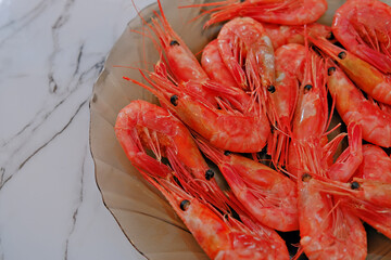 Boiled red shrimp served on a glass plate, signifying fresh seafood. Healthy and delicious meal preparation for restaurant menu.