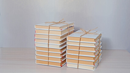 Two stacks of books tied with string, arranged on a light surface. Education and knowledge concept for learning, reading, or library theme.