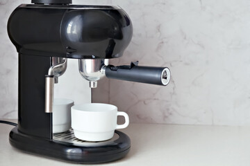 Black home espresso coffee machine with white cup on a kitchen counter, ideal for morning drink preparation and cozy breakfast setting