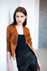 Professional fashion model wearing brown jacket and black outfit posing in studio on clean background, elegant young woman portrait for modeling agency portfolio, modern commercial beauty photography