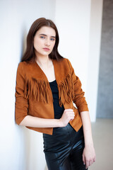 Professional fashion model wearing brown jacket and black outfit posing in studio on clean background, elegant young woman portrait for modeling agency portfolio, modern commercial beauty photography