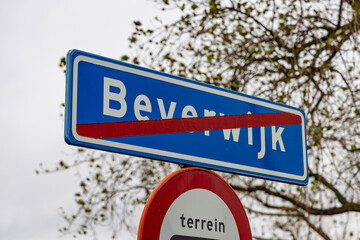 Blue Dutch road sign with a red slash indicating the end of the built-up area of Beverwijk, signaling the departure from the town.