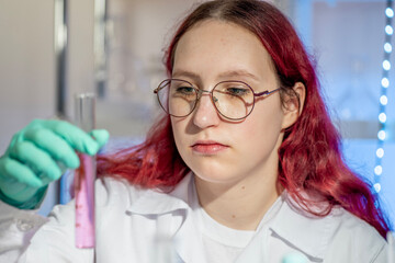 Teenage girl performing a chemistry experiment during a modern school laboratory lesson. Practical science education concept with hands-on learning, contemporary classroom and STEM teaching approach.