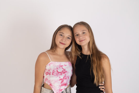 Two beautiful teenage girls posing together against white background