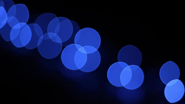 Extremely slow motion shift of large, round, deep blue bokeh light sources subtly changing focus and intensity in a dark environment design, blurred, backdrop