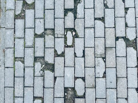 Worn Brick Pathway With Moss And Uneven Pavers, Narrow Urban Route With Weathered Grout And Small Cracks, Pedestrianfocused Composition Conveying Age And LowMaintenance Walkway Condition - Powered by Adobe