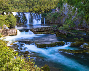 Vertical view of &Scaron;trbački Buk waterfall on the Una River, turquoise cascades flowing through forest canyon with long exposure, wild Balkan nature in Bosnia and Herzegovina, scenic travel background.