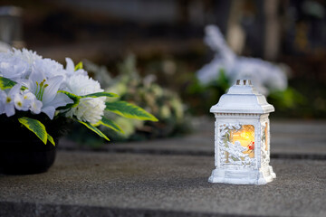 Lit burning candle at night on black stone monument in cemetery. Memory of the deceased. Expression of love