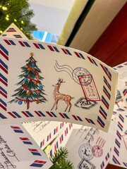 Paper Christmas garland inspired by vintage postcards and airmail envelopes, decorated with holiday tree, reindeer, and postage stamp illustrations, hanging as nostalgic festive decor indoors