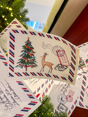 Paper Christmas garland inspired by vintage postcards and airmail envelopes, decorated with holiday tree, reindeer, and postage stamp illustrations, hanging as nostalgic festive decor indoors