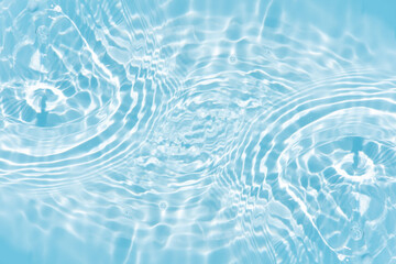 Blue water with ripples on the surface. Defocus blurred transparent blue colored clear calm water surface texture with splashes and bubbles. Water waves with shining pattern texture background.