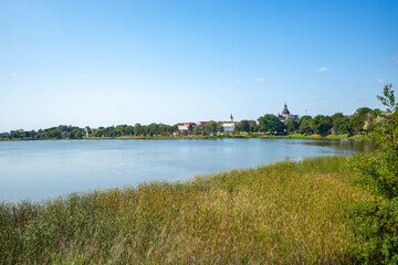 Scenic view of Nesvizh lake in Belarus, featuring distant architecture and clear blue sky.