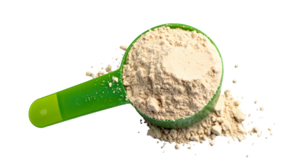 A green scoop overflowing with light brown powder, spilled, against a black background