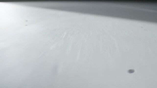 Close-up of a white surface with subtle scratches and a small mark.