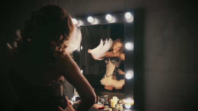 Beauty blonde hair retro lady looking into mirror hand holding fan of natural white ostrich feathers. sexy woman burlesque show actress in dressing room. Flapper girl 20s roaring twenties old style