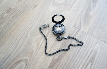 Vintage brown pocket watch with chain lying on wooden table, open cover antique mechanical timepiece, classic retro clock close-up, macro still life concept.