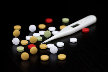 Digital thermometer and pills on table. Concept of fever, antipyretic, vitamins