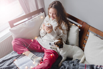 Young woman with dog drinking warm coffee at home