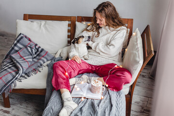Young woman with dog drinking warm coffee at home
