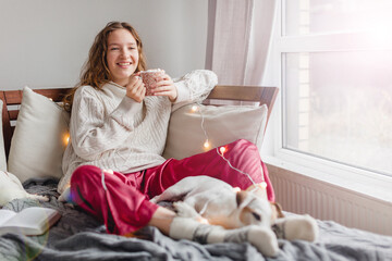 Young woman with dog drinking warm coffee at home