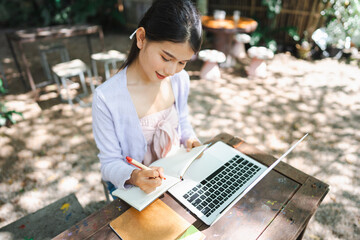 Beautiful confident freelancer asian young woman working with laptop Hands typing keyboard. digital nomad working remotely from outdoor eco cafe Workplace on nature outdoors