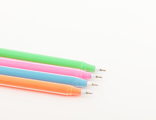 Fototapeta premium Set of bright multi-colored felt-tip pens with detached caps arranged on a white background, top view office supplies.