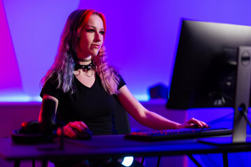Young woman gaming on desktop computer in modern studio setup