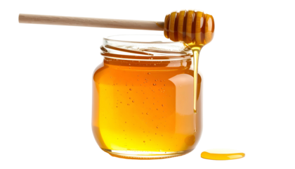 Glass jar filled with golden liquid, wooden dipper, dripping, against a black background