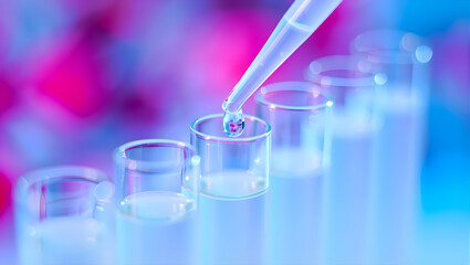 Close-up of a pipette dispensing a drop of vibrant blue liquid into a test tube, illustrating scientific research and laboratory experimentation with a futuristic aesthetic.