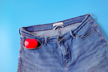 Red heart in blue jeans pocket, concept of romance.