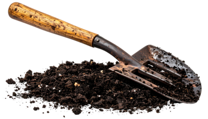 A garden hand trowel rests in a pile of dark, rich soil against a black backdrop