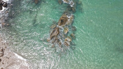 Aerial view of Bombinhas Beach in Santa Catarina, Brazil, showcasing turquoise waters and rocky shoreline.