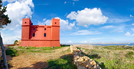 Historic watchtower St Agatha, red painted tower with battlements surrounded by rocks near Mellieha.