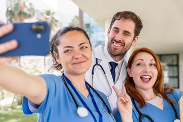 Medical healthcare team of cheerful doctors and nurses in scrubs and lab coat taking a happy selfie...