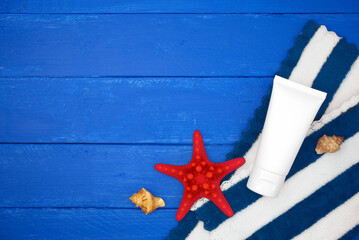Cream tube with starfish on blue wooden. Sea summer vacation background with space for the text. Top view