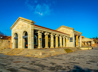 Fototapeta premium The Mtskheta Tourist Information Center near Svetitskhoveli Cathedral in Mtskheta, Georgia, features a neoclassical-style facade with tall stone columns, large glass windows, and a broad paved square 