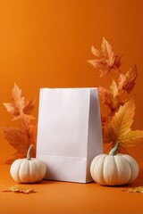 A white bag with a pumpkin and two pumpkins on the ground
