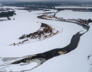 Overcast View of Frozen River Bends. Seasonal Nature / Winter to Spring Transition. A winding river with its surface partially frozen and covered in snow revealing dark open water at the deepest bend.
