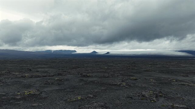 Dark Volcanic Terrain and Melting Glacier in Distance