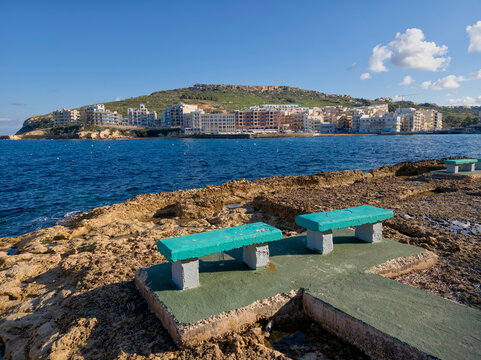 Marsalforn, Malta — coastal town with rocky shoreline and azure Mediterranean Sea - Powered by Adobe