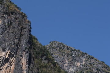 Panoramic autumn mountain landscape featuring a high peak view over a misty forest valley with green trees and a lake under a cloudy sky in Laos