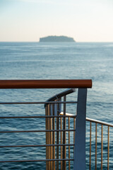 idyllic seascape with bridge railing and an island 