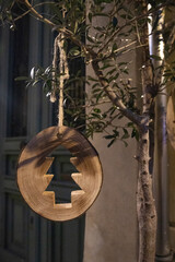 handmade wooden christmas ornament hanging on an olive tree branch